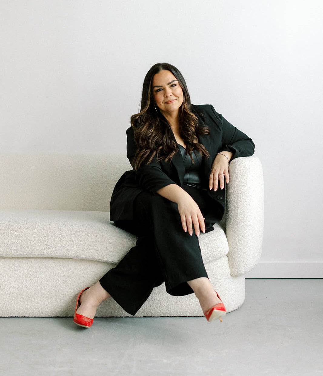 Smiling woman sitting on a white sofa, professional real estate agent Colleen Hungerford